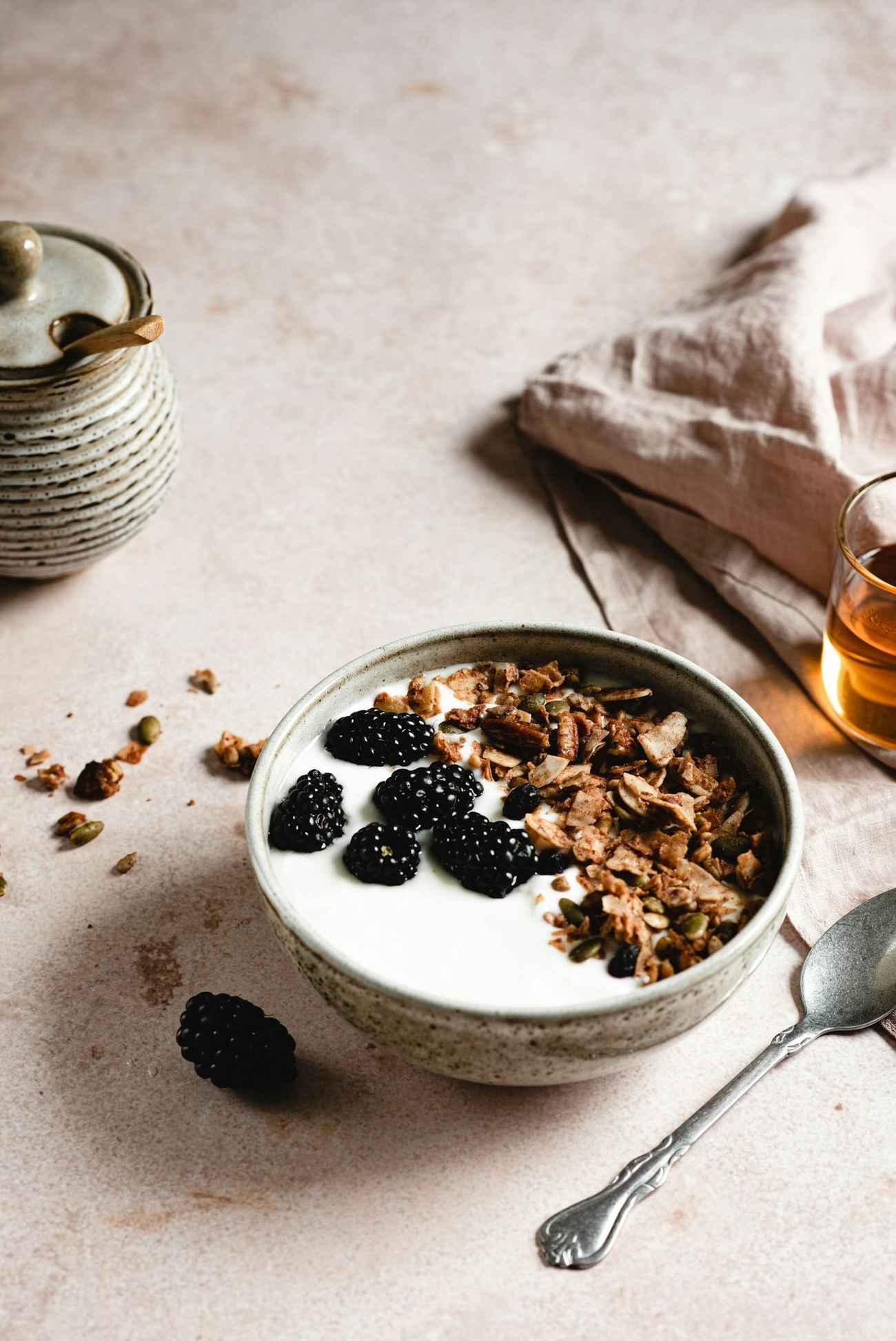 A bowl of yogurt with granola and blackberries