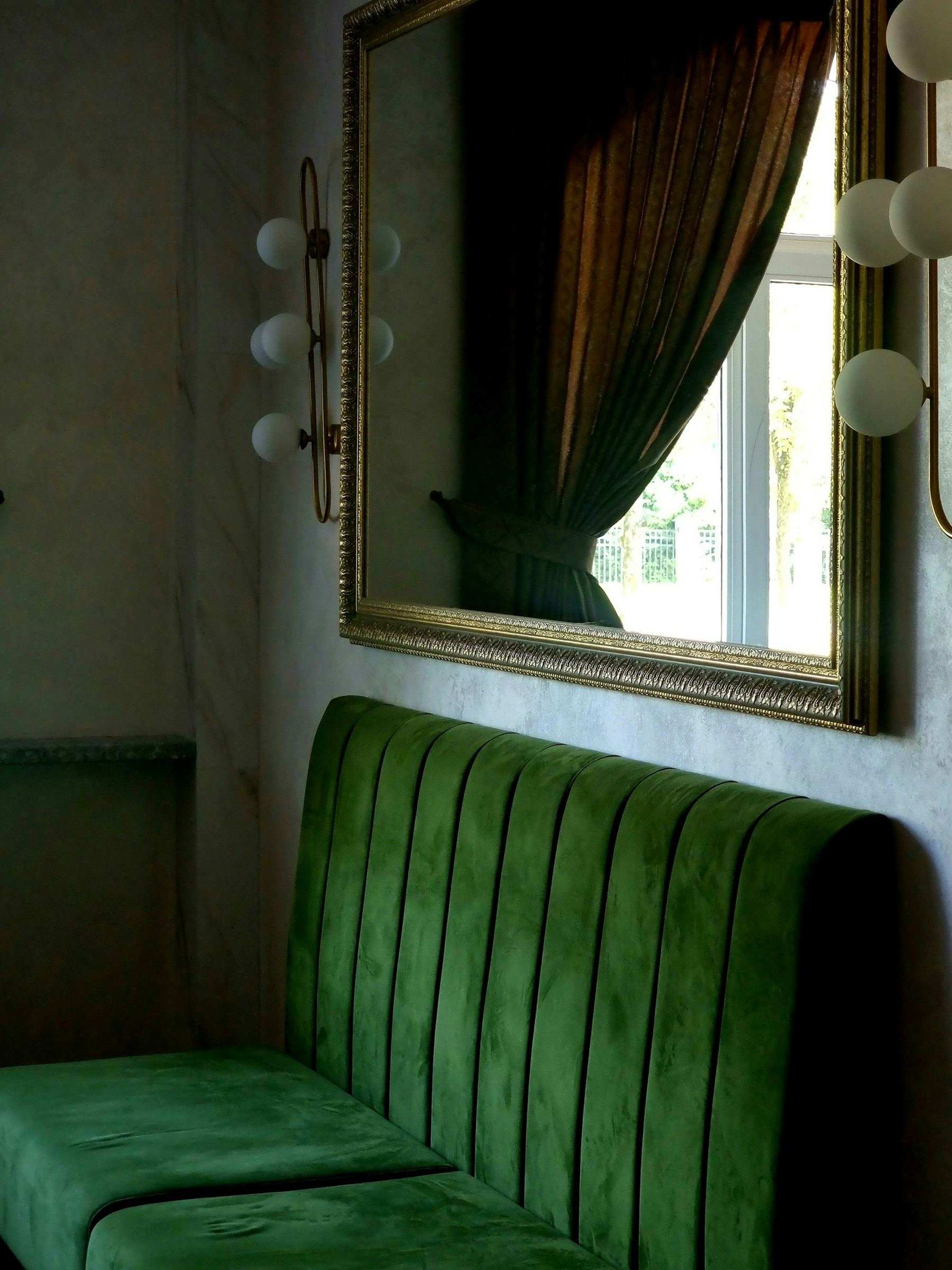 Green velvet chairs and a gold-framed mirror