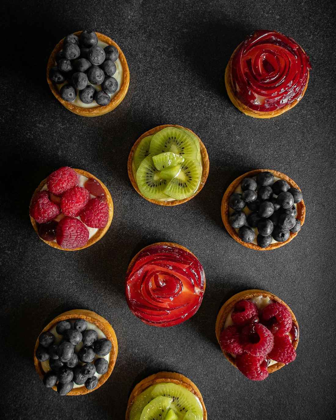 An assortment of fruit tarts with berries and kiwi